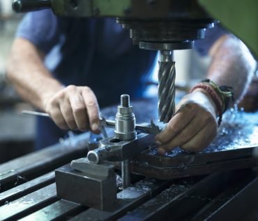 Worker operating industrial machine in metal workshop.